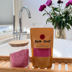 Cranberry Bath Dust naast een roze bad in een sfeervolle badkamer